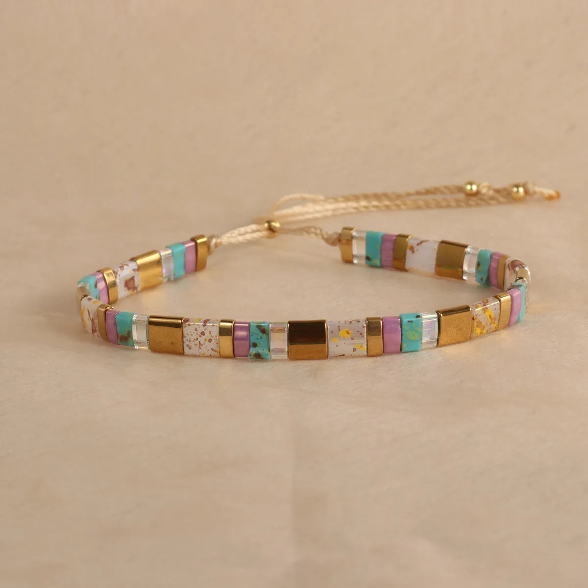 Geometric beaded bracelet with round elements in milky white, black, green, blue, or red.