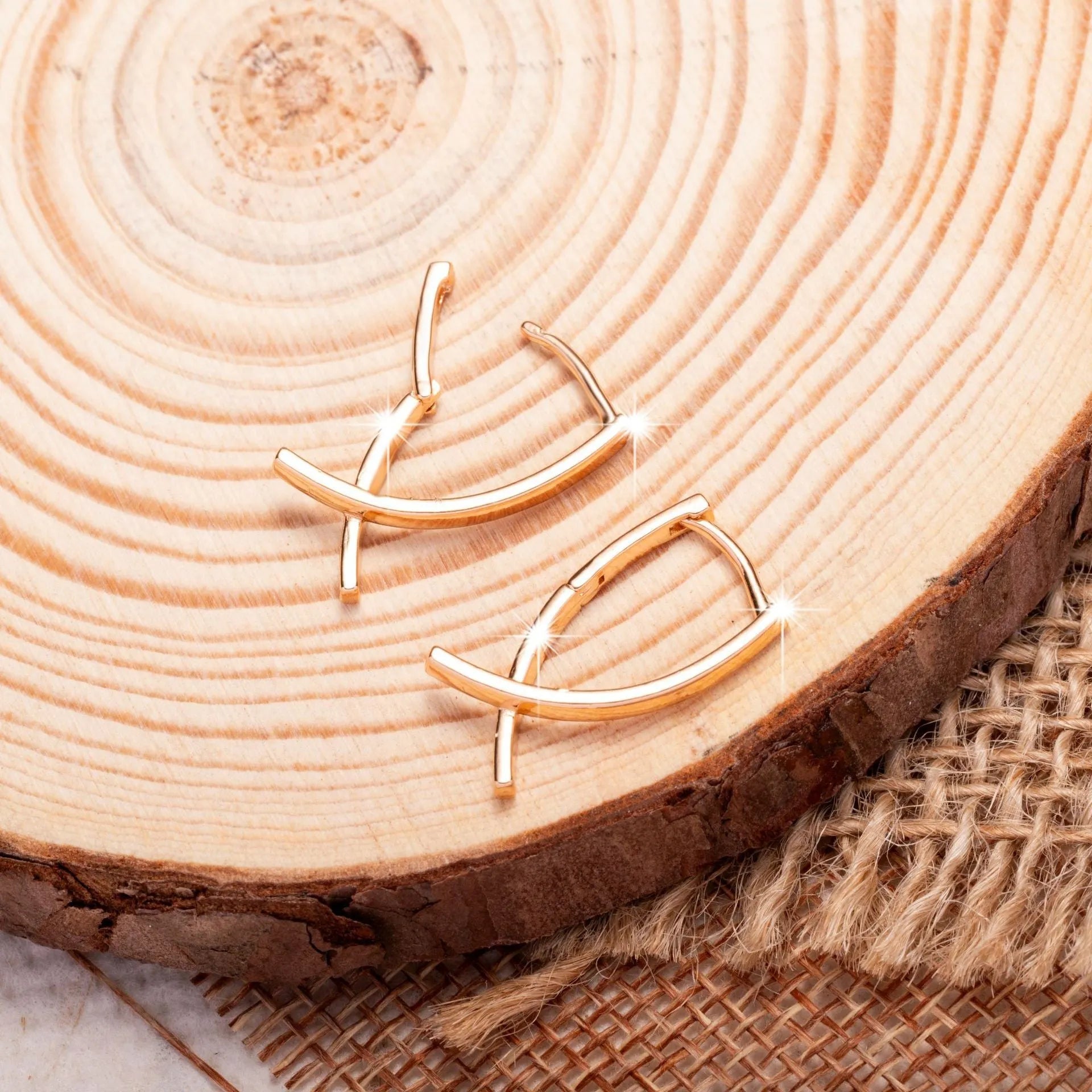 A pair of rose gold coloured cross shaped earrings made from polished copper.