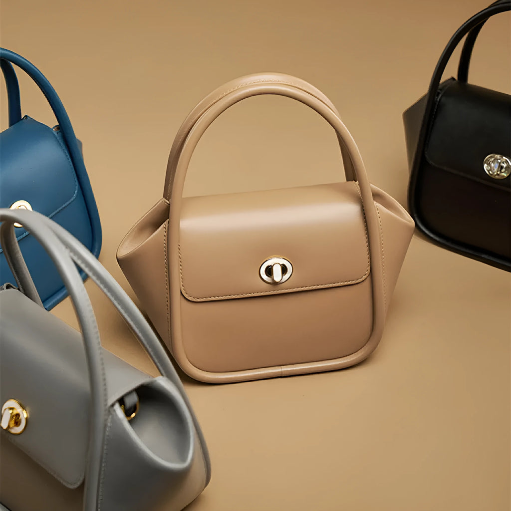 Women's wing-shaped leather tote bag with a latch buckle, shown in Atlantic blue with a cross-body strap.