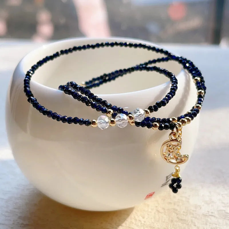 Close-up of a women's multi-layer bracelet with three blue gold sand stone rings on a wrist.