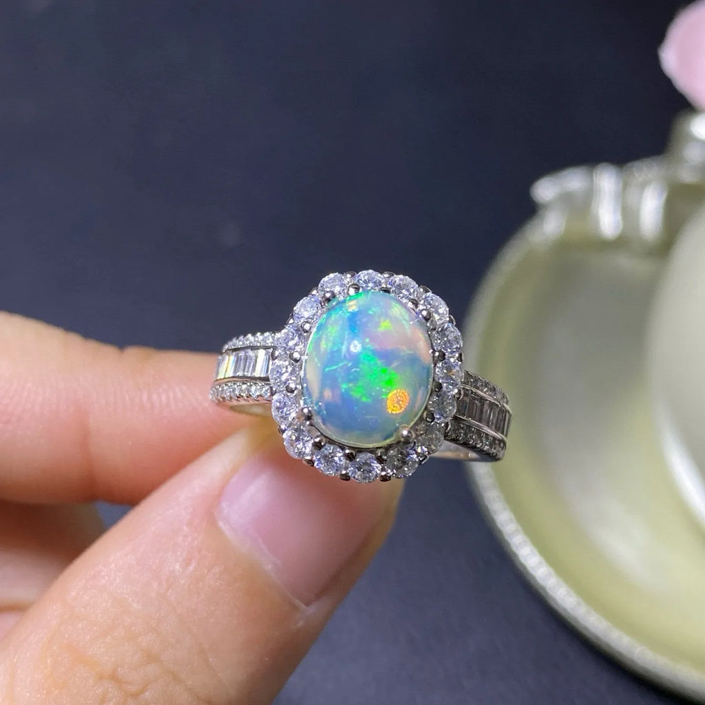 Adjustable opening opal ring in sterling silver with gold tone plating on a model's hand