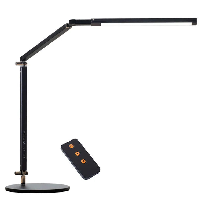 Aluminium clip-on desk lamp with adjustable arm and remote control on a wooden desk.