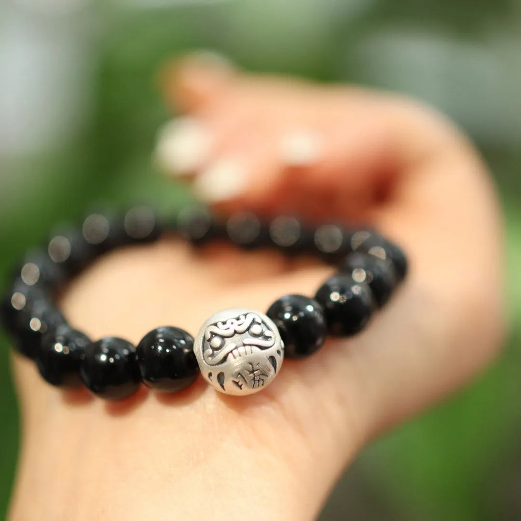 Natural black agate bead bracelet with a sterling silver clasp on a wrist.
