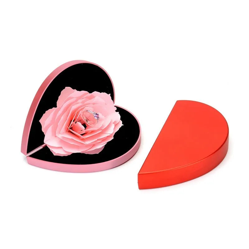 Red heart-shaped plastic ring box on a white background, showing its rotating mechanism.