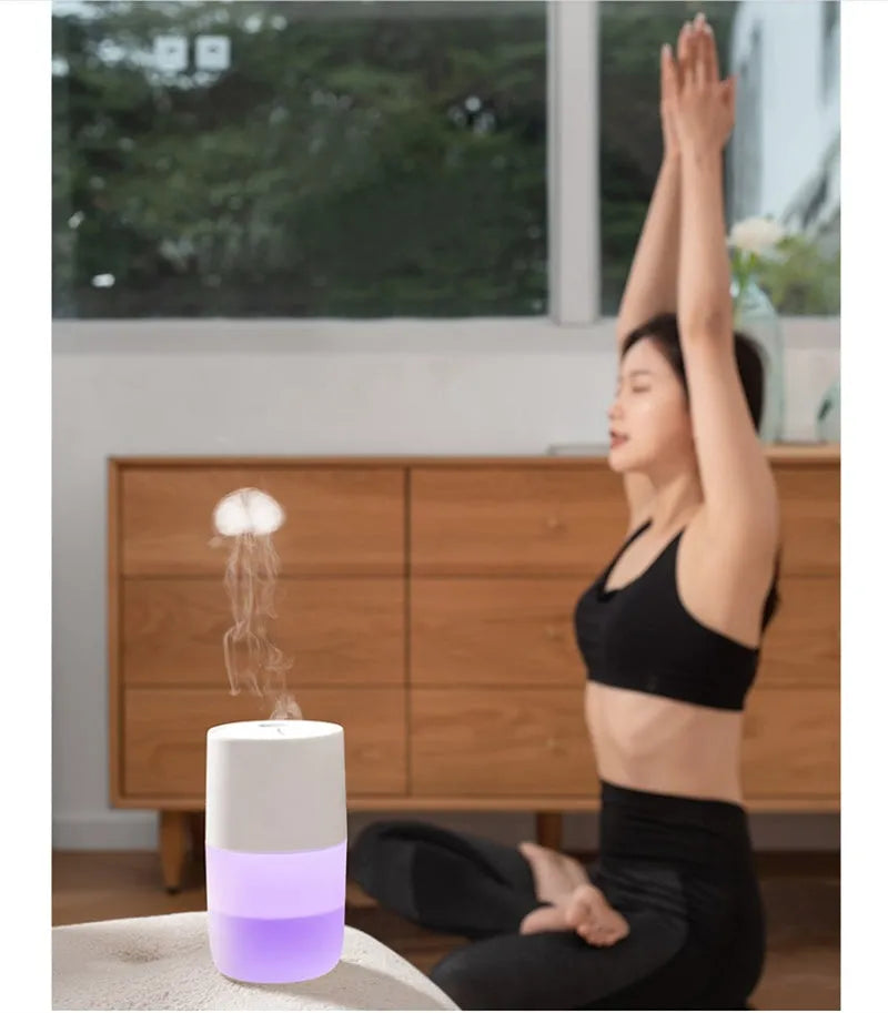Mini portable jellyfish-shaped ultrasonic humidifier in black, with USB cable and essential oil bottle on a desktop