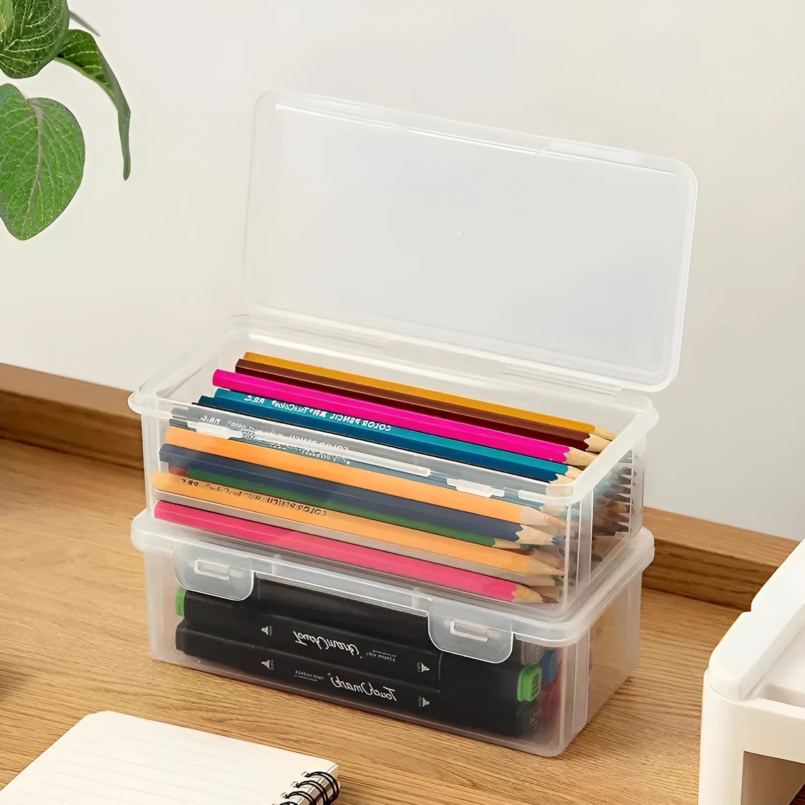 Transparent plastic stationery storage box containing colour pencils and drawing supplies