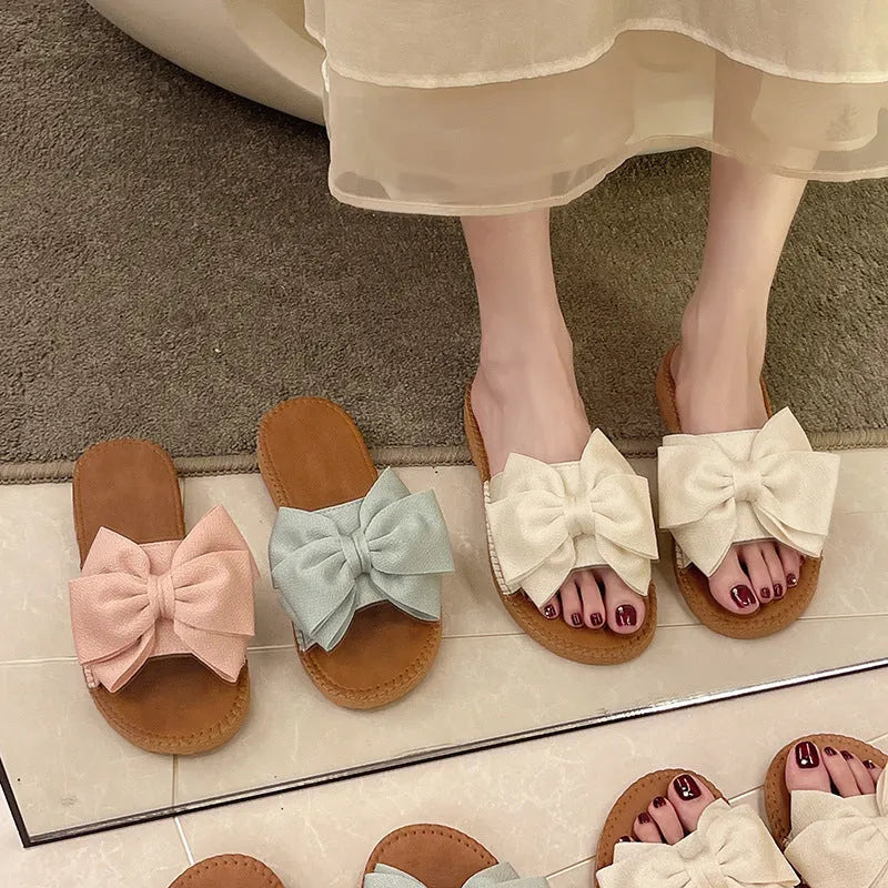 Women's beige suede slip-on sandals with bow detail and flat rubber sole