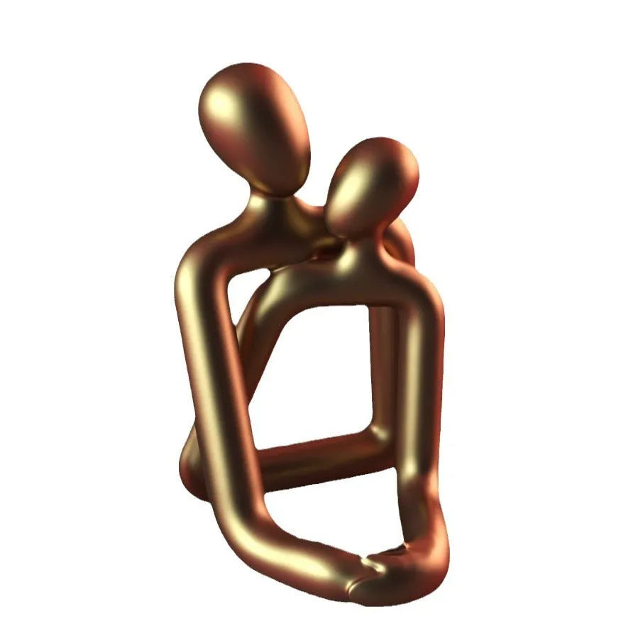 Modern resin sculpture of an embracing couple in milky white or gold finish on a wooden surface.