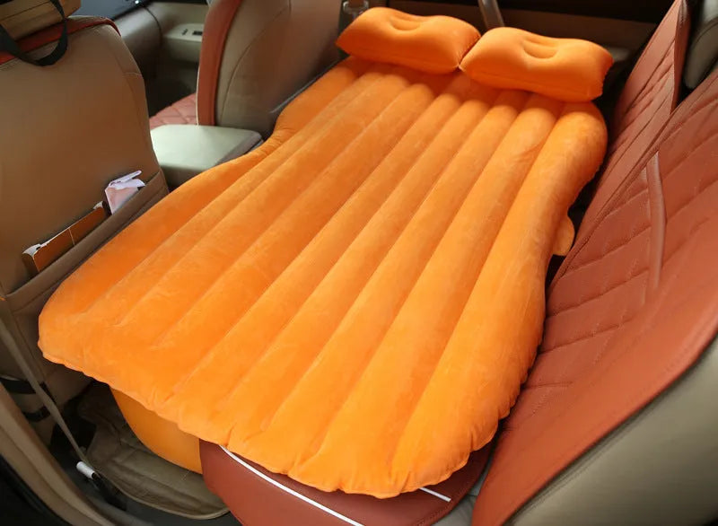 Black inflated car bed with flocked surface and two pillows inside a five-seater vehicle.