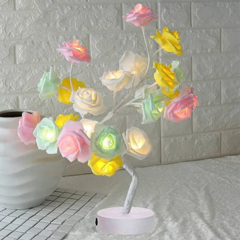 White and red rose shaped LED table lamp with bonsai tree base on a wooden table.