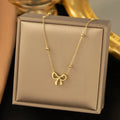 Gold coloured bow pendant necklace on a cross chain, showing adjustable length.