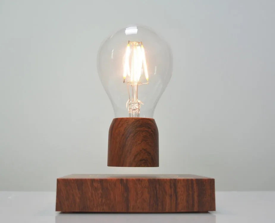 Magnetic levitation light bulb floating above wood-effect base with international plug adapters