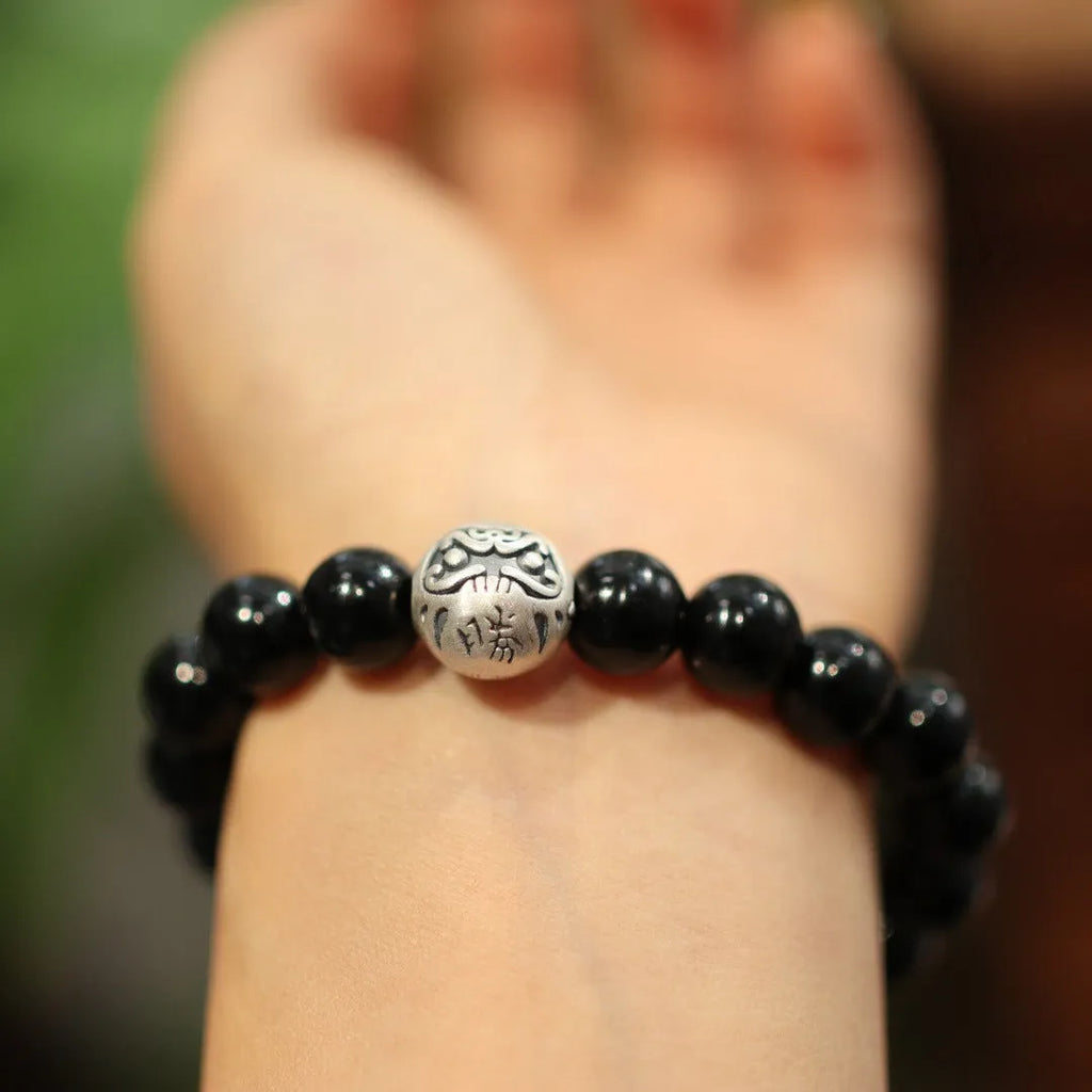 Natural black agate bead bracelet with a sterling silver clasp on a wrist.