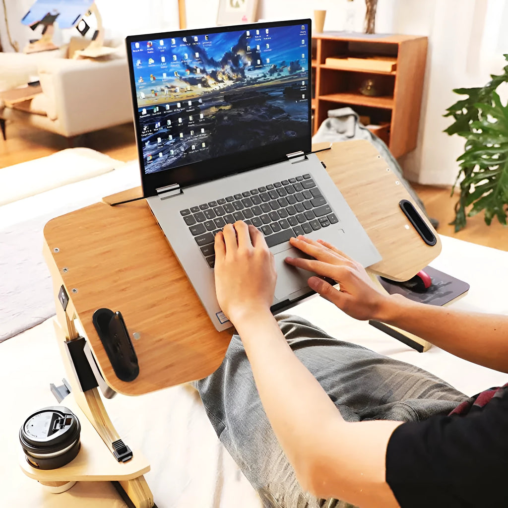 Wooden folding computer desk with adjustable angle shown on a bed in black finish.