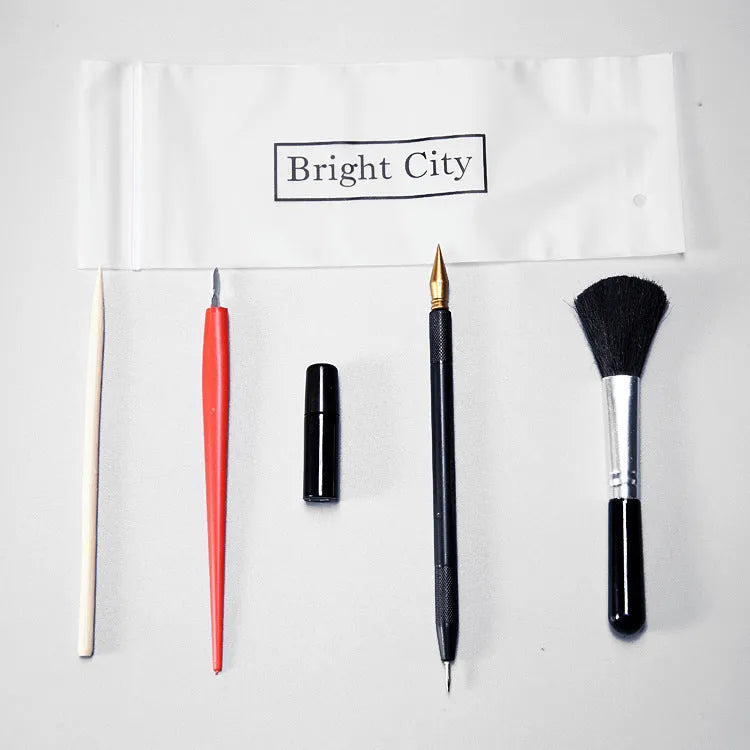 Scratch art tool kit with scraping pens, brushes, repair liquid, and bamboo sticks on a craft table.