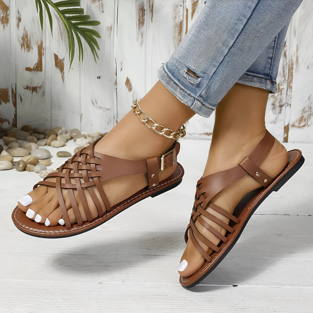 Black Roman style beach slippers with cross straps and flat buckle closure on open toe design