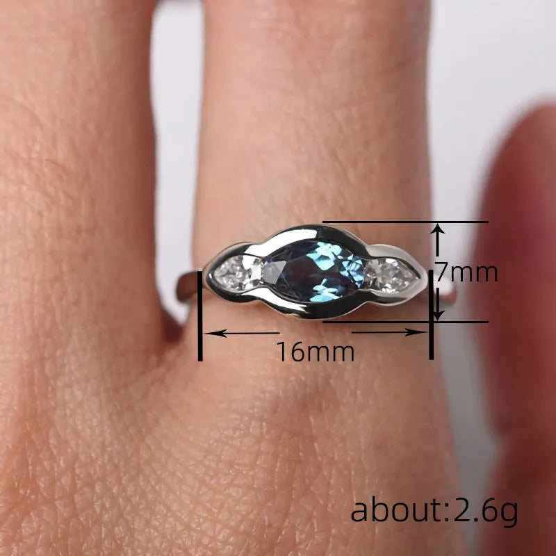 Geometric ellipse-shaped ring in white gold colour with zircon inlay, shown on a hand.