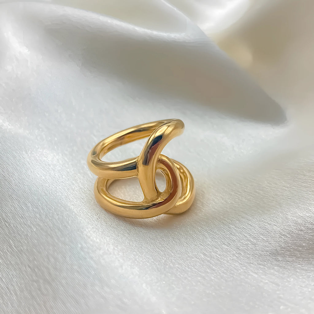 Women's stainless steel adjustable knotted open ring in gold or steel colour on a grey background.
