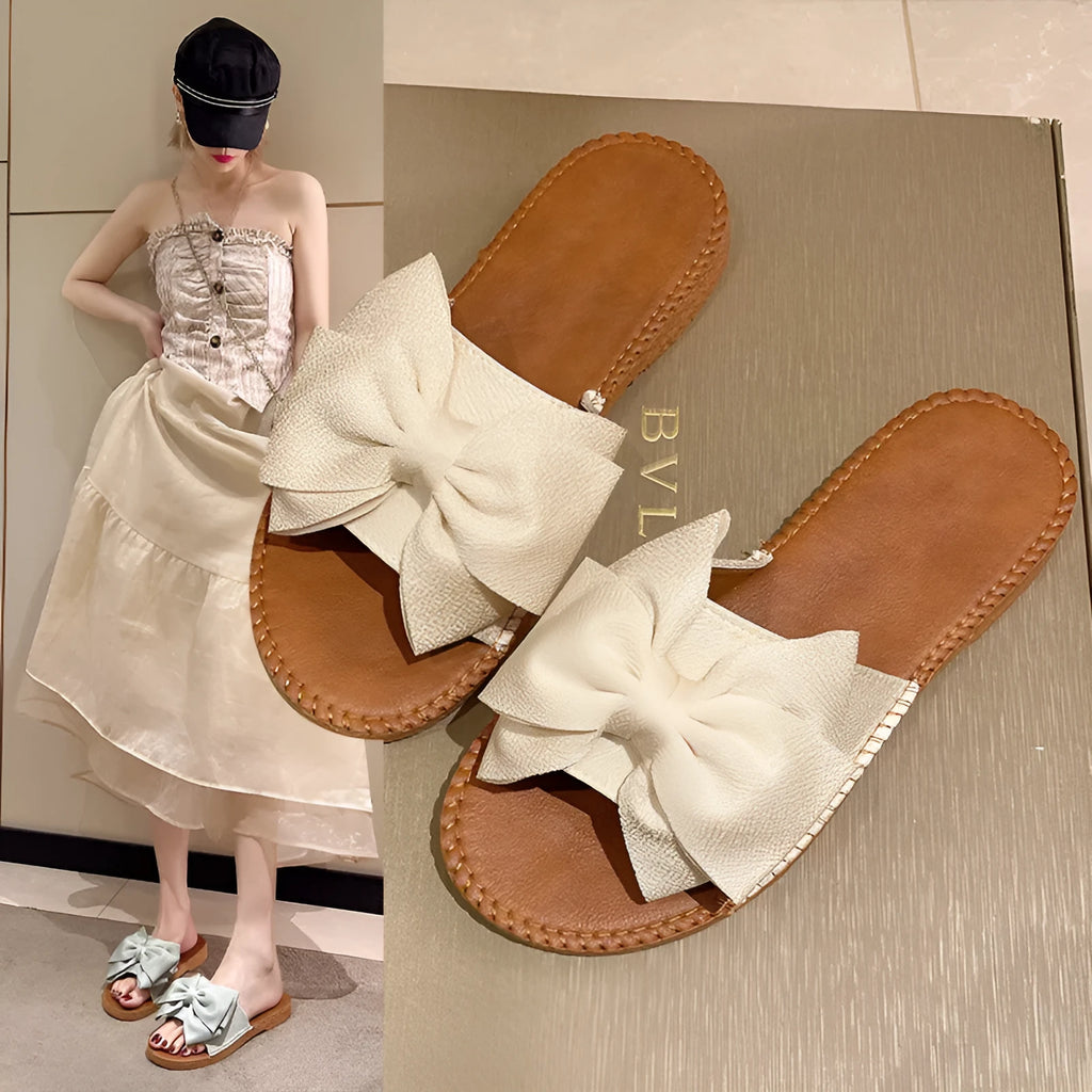Women's beige suede slip-on sandals with bow detail and flat rubber sole