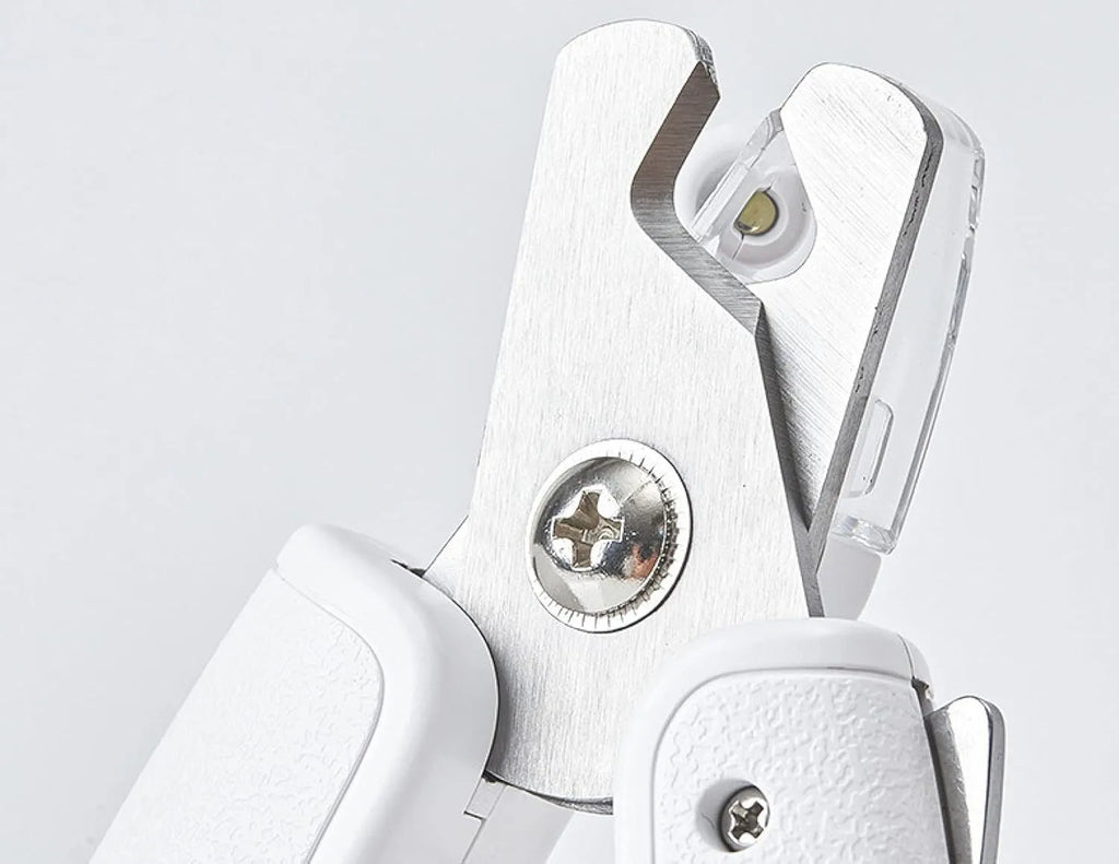 White pet nail clippers with LED light on blade and transparent anti-splash guard, shown with a nail file.