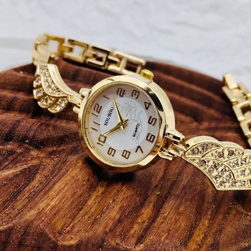 Stainless steel women's watch with round dial on wrist, showing gold colour surface and vachette clasp.