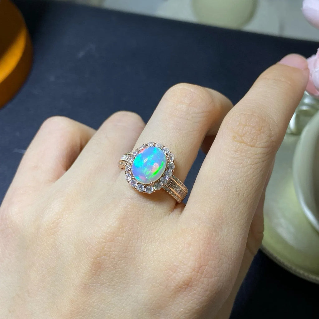 Adjustable opening opal ring in sterling silver with gold tone plating on a model's hand
