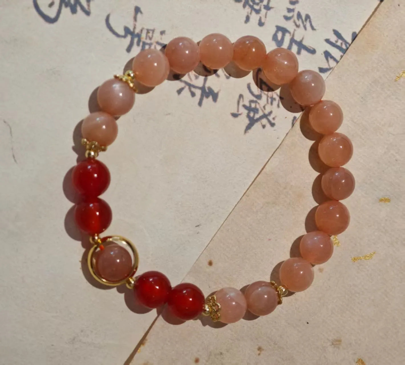 Handmade ethnic-style bracelet with sand orange Sunstone and 8mm red agate beads in a star pattern.