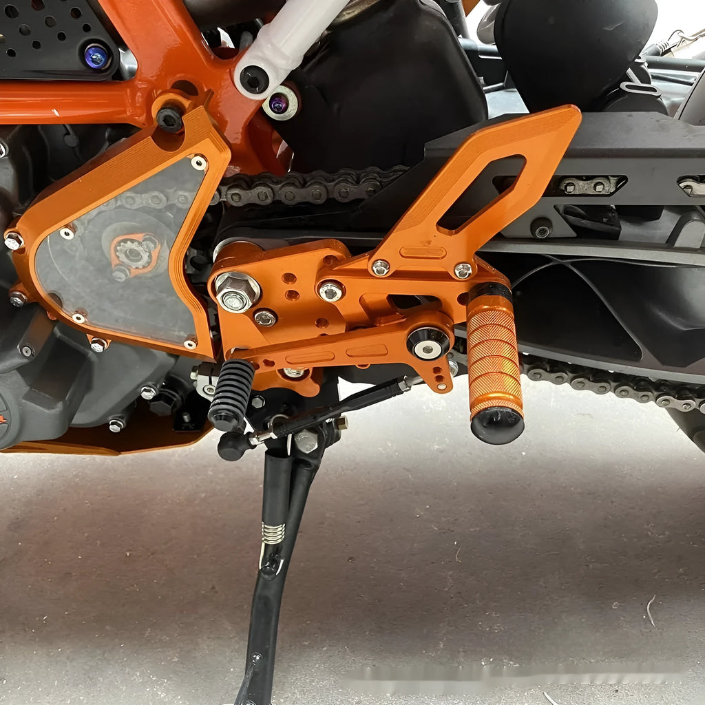 Black and orange KTM Duke motorcycle pedal support bracket assembly