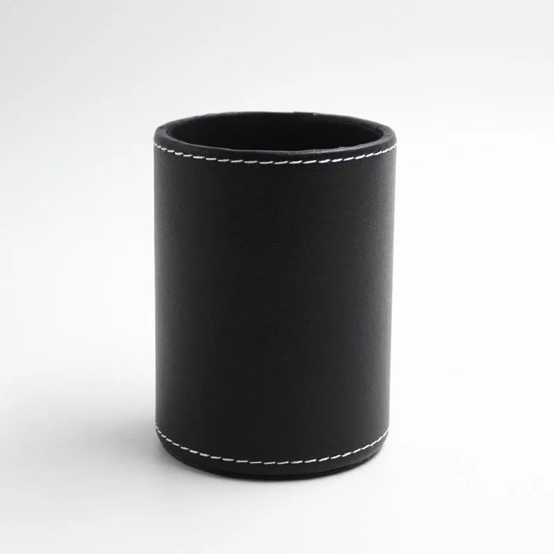 Round black leather pen container on desk holding writing instruments