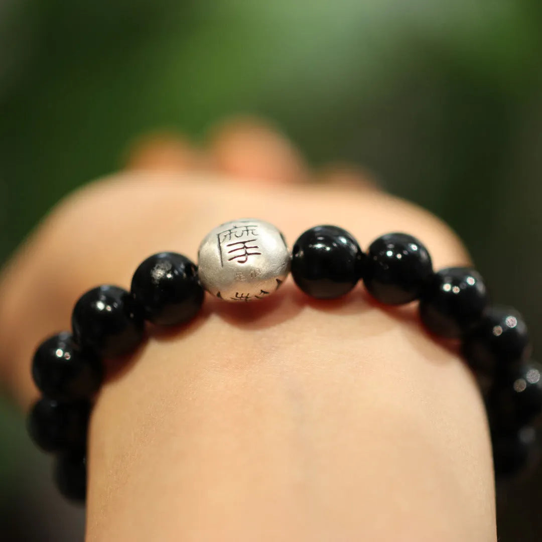 Natural black agate bead bracelet with a sterling silver clasp on a wrist.