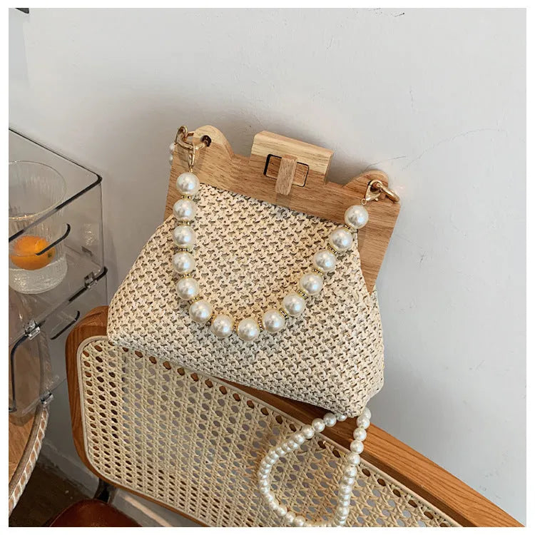 Women's woven straw shoulder bag with pearl chain strap showing interior organisation compartments