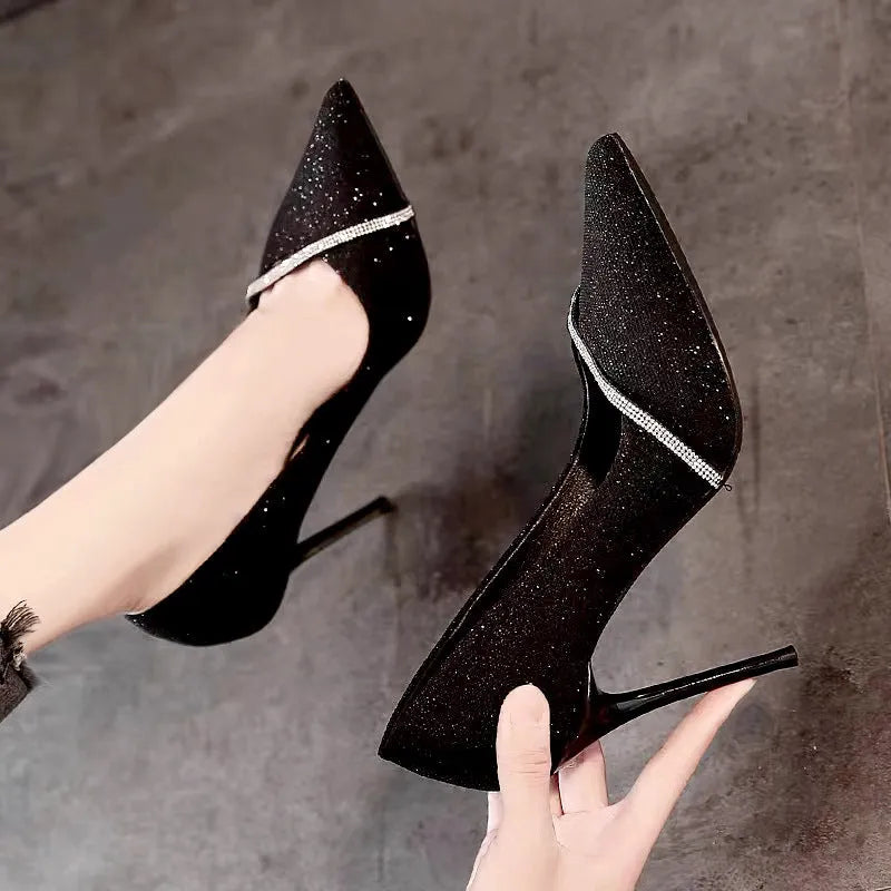 Gold and black women's stiletto pointed toe high heels on a white background.