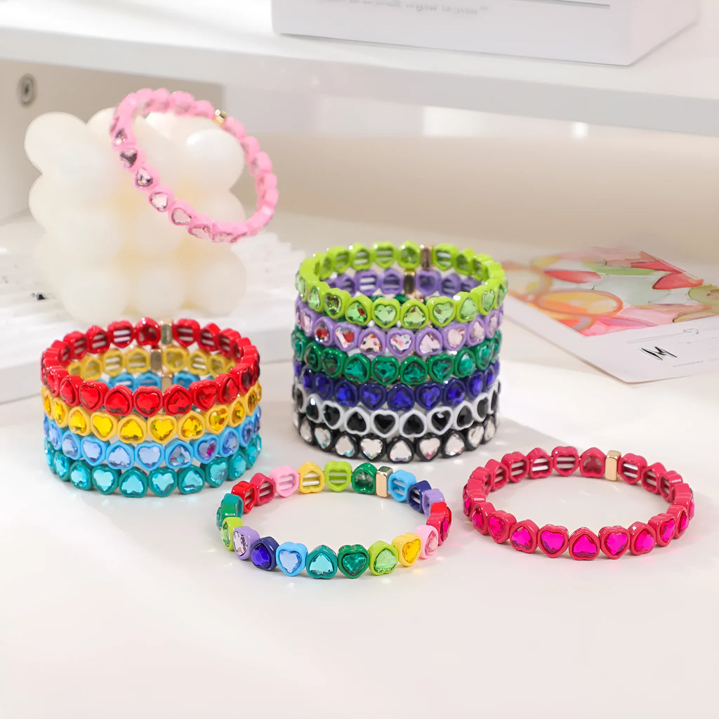 Colourful enamel heart-shaped charm on a stretch bracelet with diamond-textured alloy finish.