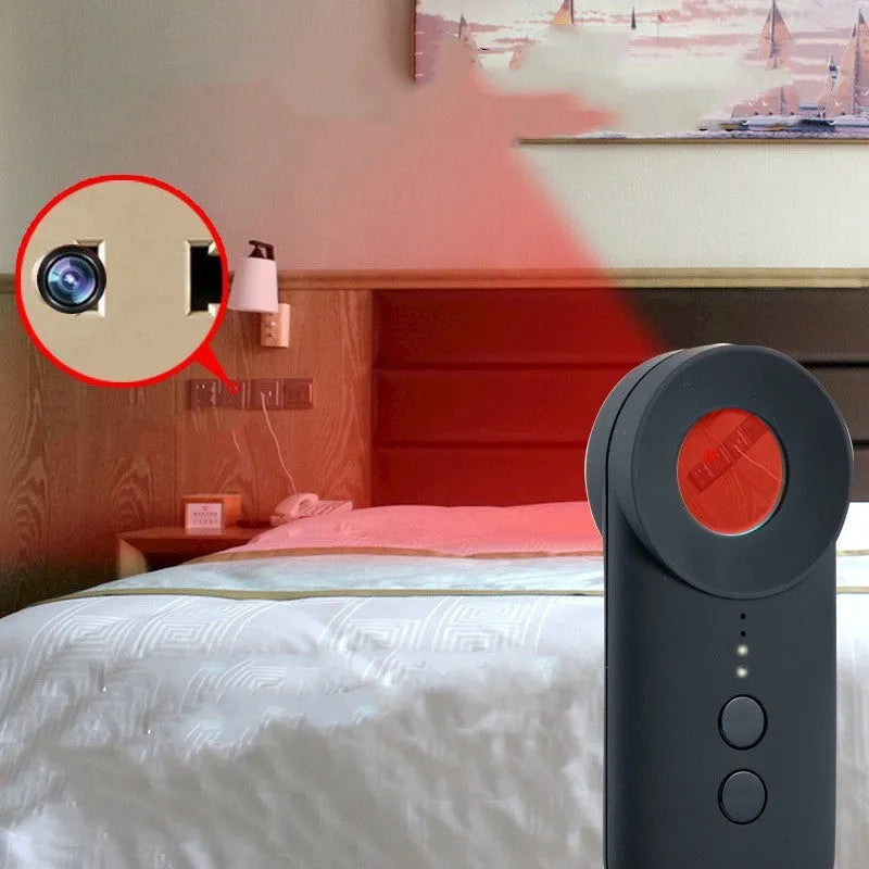 Black portable GPS and hidden camera detector with USB charging cable on a grey background.