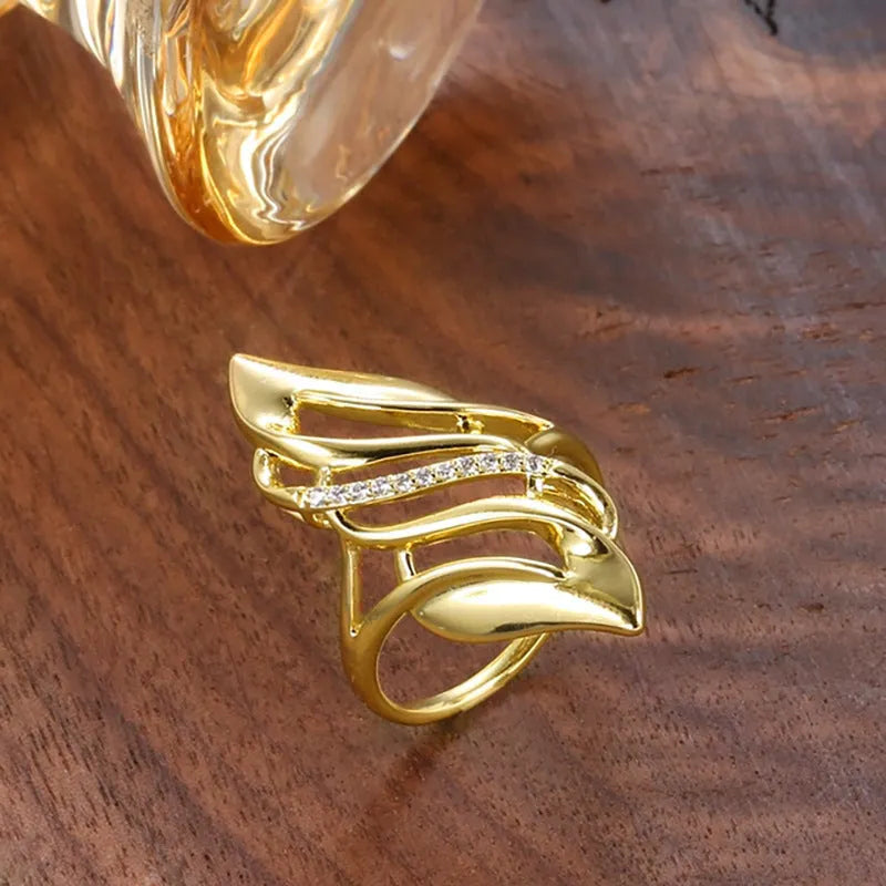 Women's copper ring with exaggerated curved design and gold-coloured finish showing side profile
