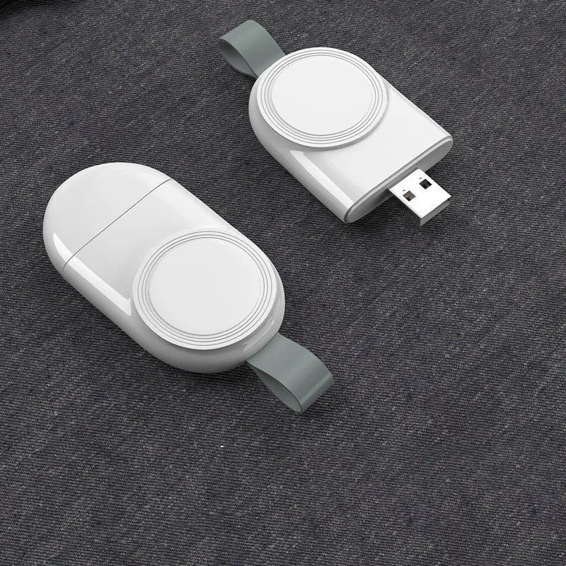Portable white wireless charging dock for Apple Watch on a desk next to a laptop.