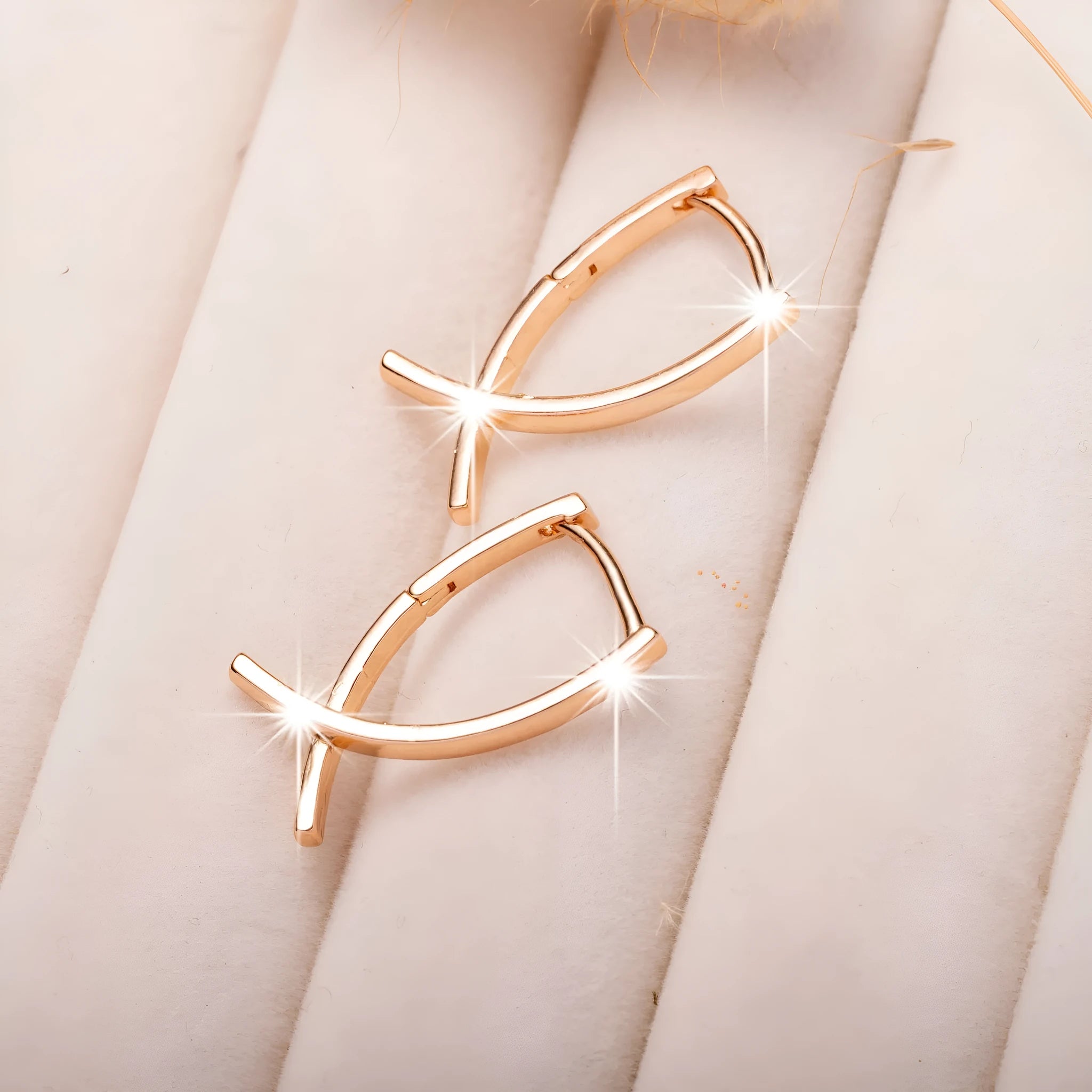 A pair of rose gold coloured cross shaped earrings made from polished copper.