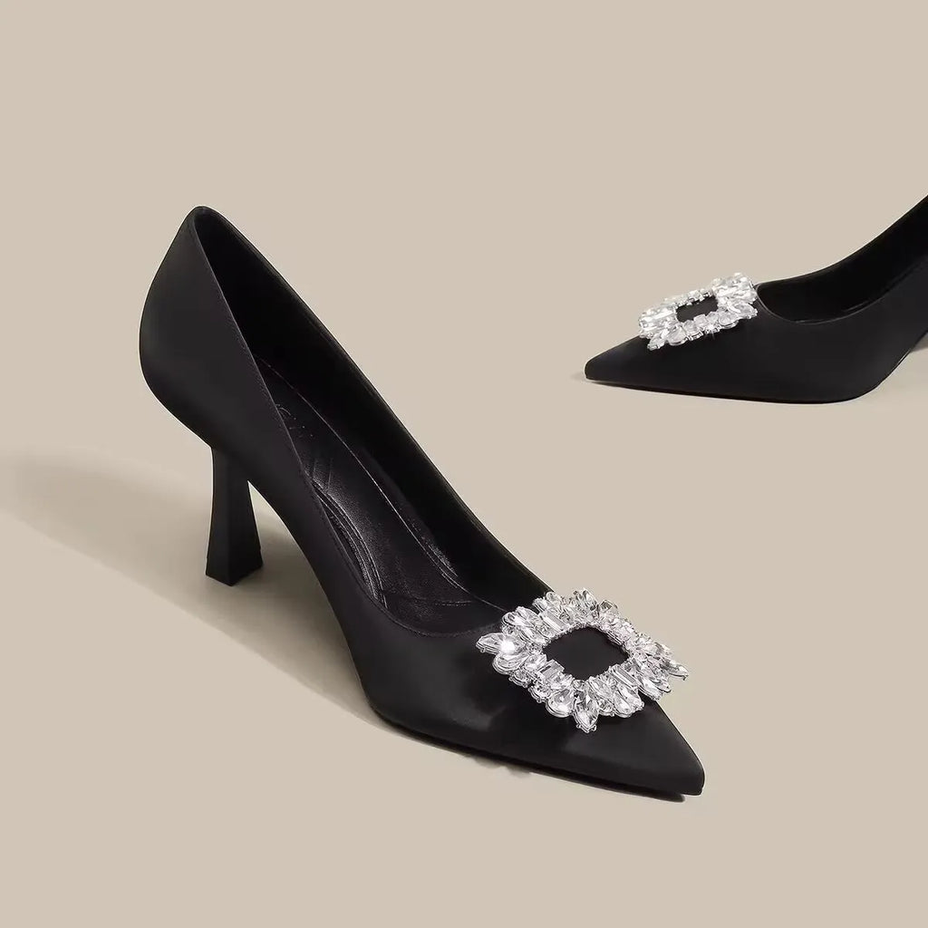 Creamy-white or black women's pointed toe high heels with a stiletto heel on a plain background.