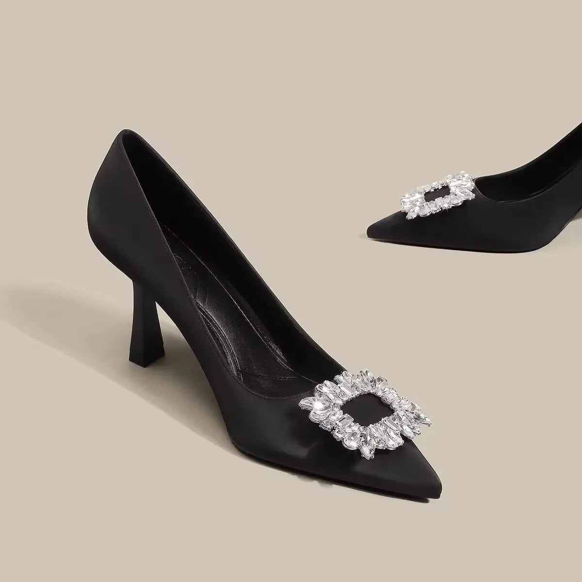 Creamy-white or black women's pointed toe high heels with a stiletto heel on a plain background.