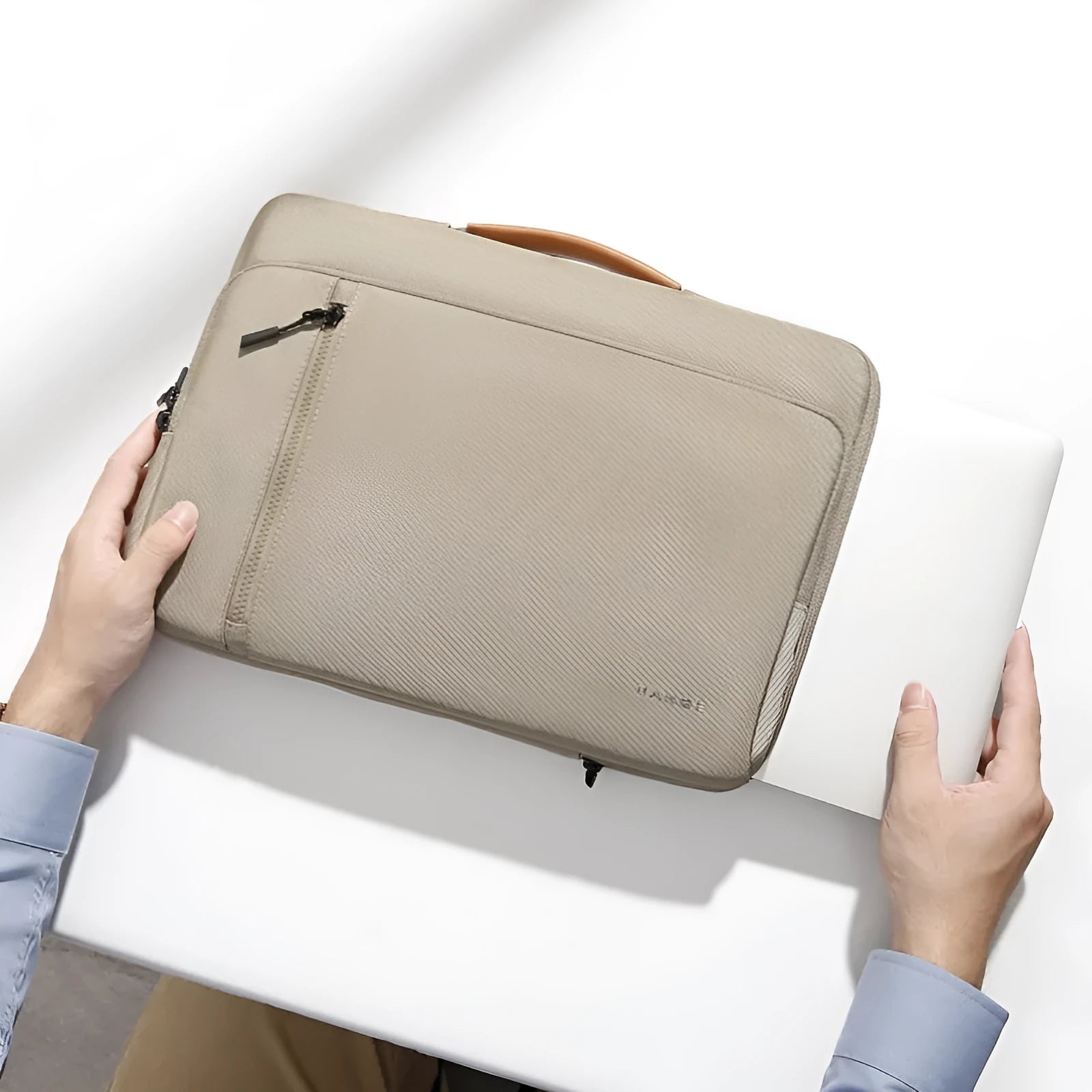 Khaki nylon laptop sleeve with zip closure and visible sewing lines next to a 14-inch notebook