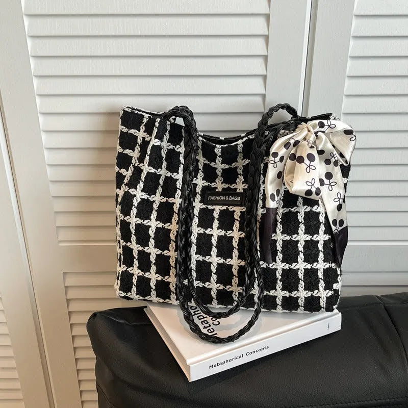 A black woven wool horizontal square shoulder bag showing external sandwich pocket and internal organiser compartments.