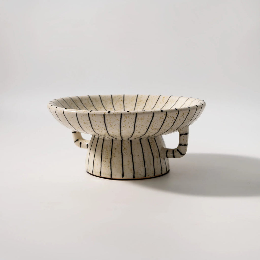 Black and white striped synthetic resin fruit plate on a wooden table.