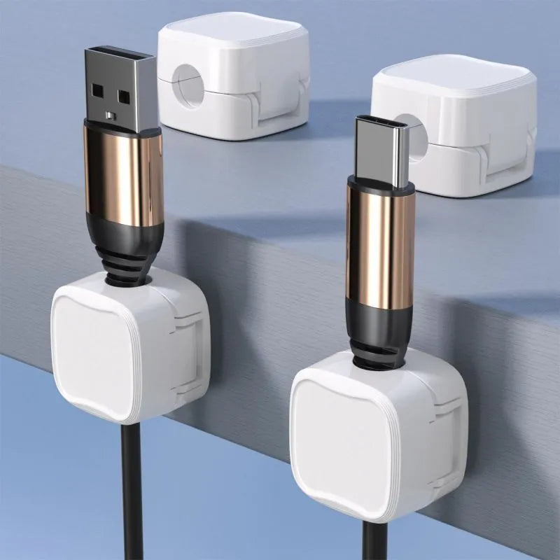 White and black magnetic adhesive cable clips holding a USB cable against a wooden desk.
