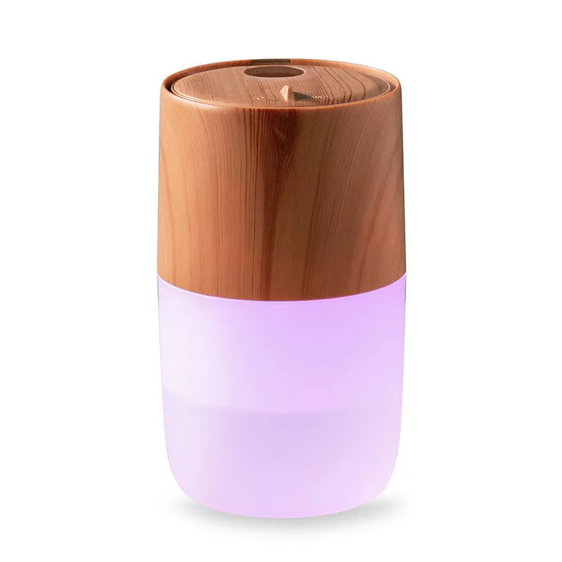 Mini portable jellyfish-shaped ultrasonic humidifier in black, with USB cable and essential oil bottle on a desktop