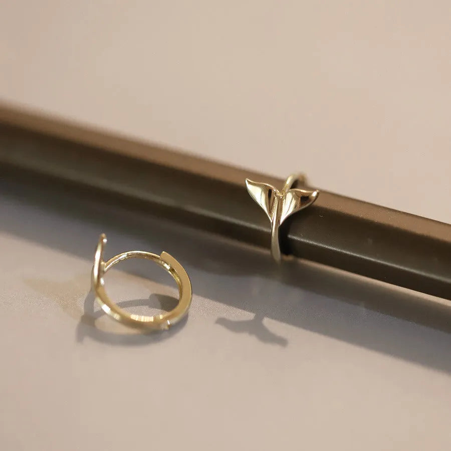 A pair of smooth sterling silver fishtail hoop earrings with a gold plated finish.