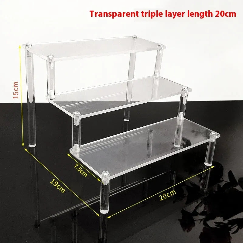 Transparent acrylic ladder display rack with three trapezoidal tiers showing blind box figurines on a desk