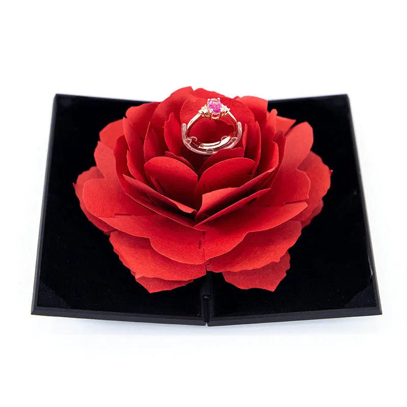 Red heart-shaped plastic ring box on a white background, showing its rotating mechanism.