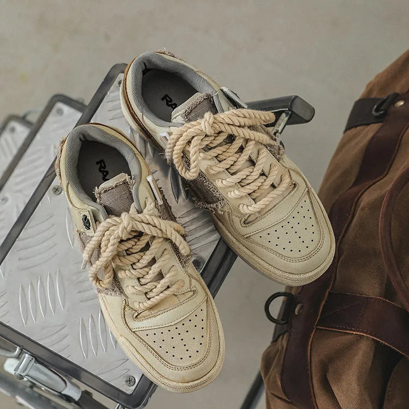 Beige low-top vintage skate shoes with round toe and front lace-up closure on a solid background.