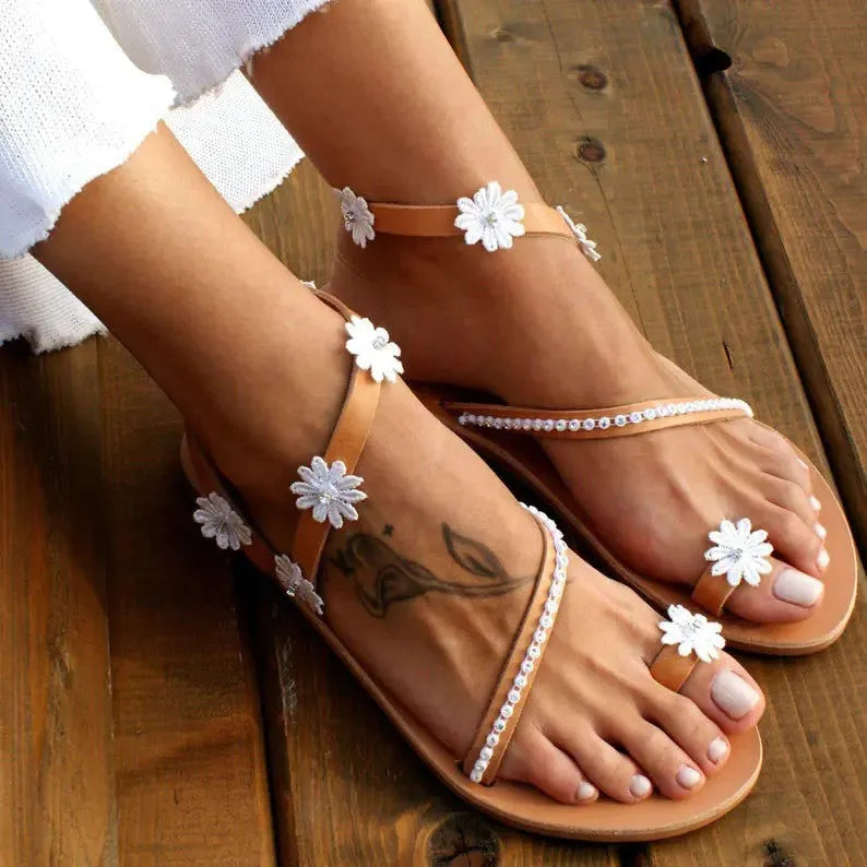 Brown women's Roman sandals with floral embroidery, flat rubber sole, and sleeve-on design.