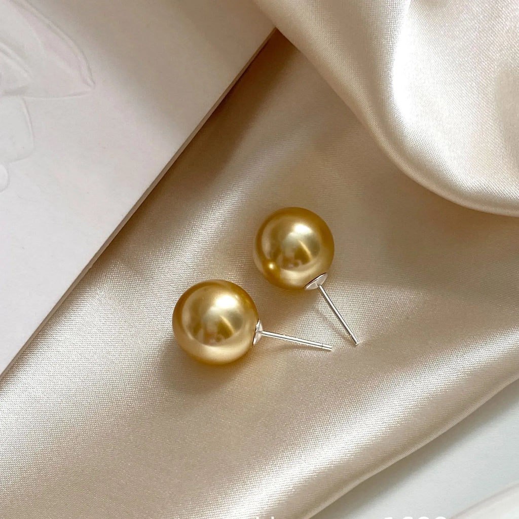 A pair of women's silver pearl stud earrings with geometric star accents on a grey background.